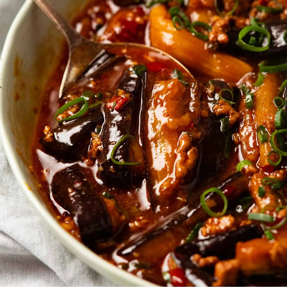 Stir-fried dish with eggplant and vegetables in a red sauce, served in a bowl.